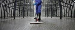 Worker cleaning an empty warehouse floor